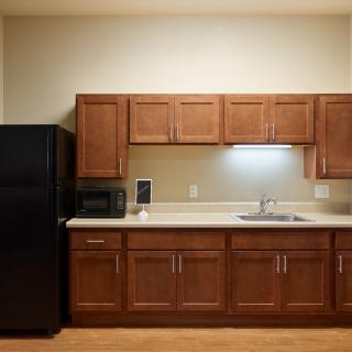 A kitchen with wooden cabinets, a black refrigerator, a microwave, and a sink.