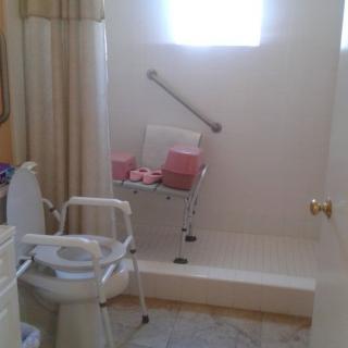 An accessible bathroom featuring a shower chair and grab bar for safety.