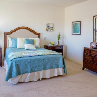 A cozy bedroom with a wooden bed frame, turquoise bedding, matching nightstands, and elegant decor.