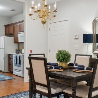 A cozy dining area with a table set for four, adjacent to a kitchen featuring wooden cabinetry and modern appliances.