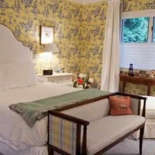 A cozy bedroom interior with floral wallpaper and elegant furnishings.
