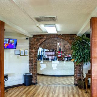A cozy restaurant interior featuring a reception area with brick walls and wooden accents.
