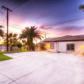 A serene residential house with a spacious driveway and palm trees at sunset.