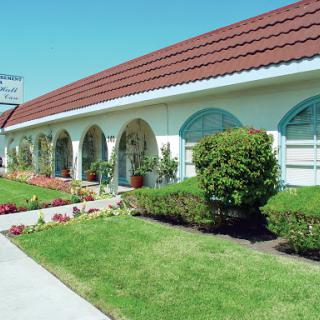 A charming building with arched windows surrounded by lush greenery and vibrant flowers.