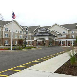 A large building with an American flag, featuring a parking lot and landscaped entrance.