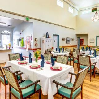 A well-set dining area with tables and chairs arranged neatly, featuring elegant table settings.