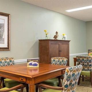 A dining room with a wooden table, patterned chairs, and a cabinet against the wall.