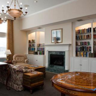 A cozy living room featuring a fireplace, bookshelves, and elegant furniture.