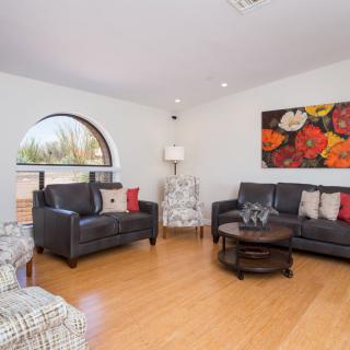 A modern living room with dark sofas, a round coffee table, and floral artwork on the wall.