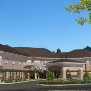 A modern residential building with landscaped surroundings under a clear blue sky.