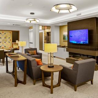 A modern lounge area featuring comfortable seating, a large TV, and elegant lighting.