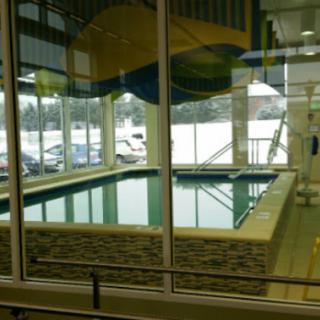 A serene indoor swimming pool surrounded by large windows showcasing a snowy exterior.