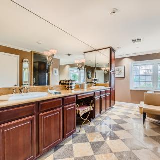A spacious and luxurious bathroom featuring a large vanity with a mirror and elegant tile flooring.