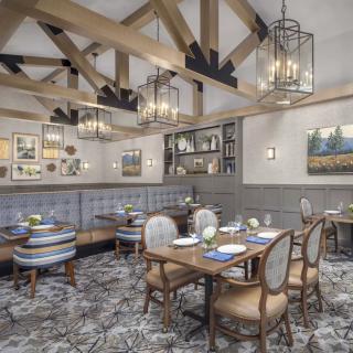 A beautifully designed restaurant dining area featuring elegant chandeliers, wooden beams, and stylish furnishings.