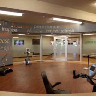 A modern gym featuring various exercise equipment and motivational words on the walls.