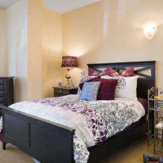A cozy bedroom with elegant decor featuring a dark wood bed and floral bedding.