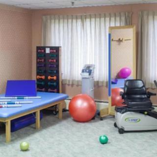 A rehabilitation room equipped with various exercise tools, including fitness balls and a therapy table.