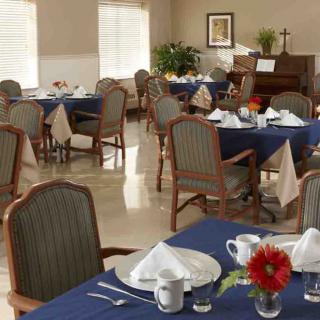 A dining room with neatly arranged tables and chairs, featuring blue tablecloths and set for a meal.