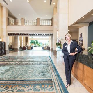 A person in business attire standing in a spacious hotel lobby with elegant decor.