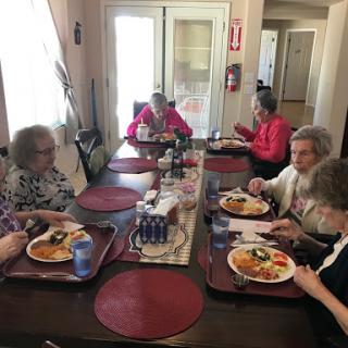 A group of elderly individuals enjoying a meal together around a dining table.