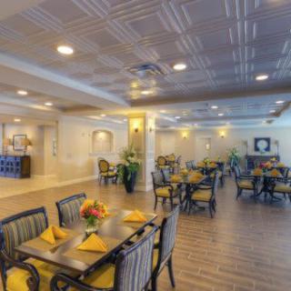 A spacious and elegantly decorated dining room with arranged tables and chairs, adorned with centerpieces of vibrant flowers.