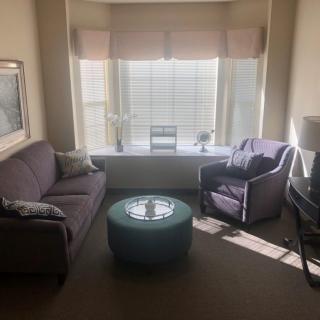A cozy living room with a sofa, armchair, and a coffee table by the window.