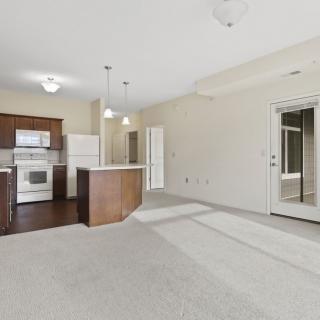 A modern, empty apartment interior showcasing an open floor plan with a kitchen and living area.