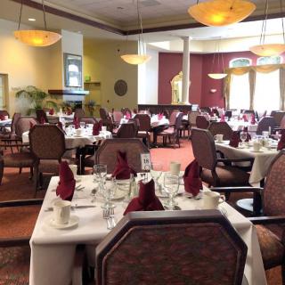An elegant restaurant dining room set with tables and chairs, featuring folded napkins and refined decor.