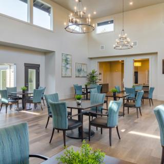 A spacious, well-lit dining area with modern decor and elegant chandeliers.