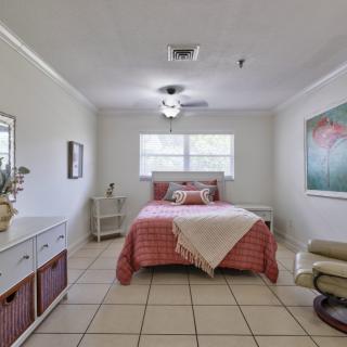 A cozy bedroom with a neatly made bed, a comfortable chair, and decor accents.