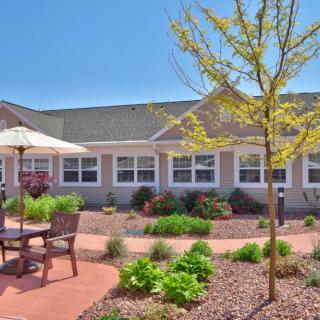 A sunny outdoor patio area with garden landscaping and seating in front of a building.