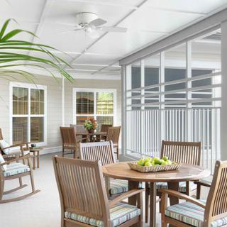 A cozy patio area with tables and chairs, featuring plants and a ceiling fan.