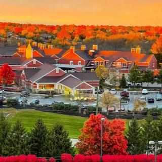 A vibrant autumn sunset illuminating a scenic landscape with colorful trees and buildings.