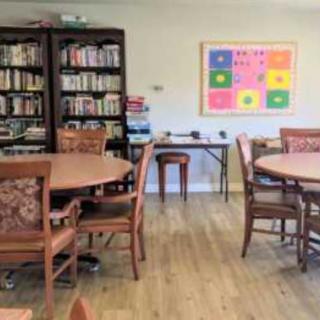 A cozy library room with bookshelves, round tables, and wooden chairs.
