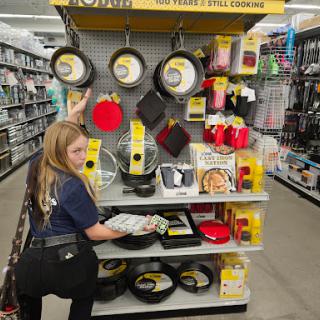 A shopper browsing through a display of cookware in a retail store.