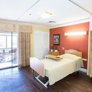 A well-furnished and comfortable hospital room with a bed and access to a balcony.