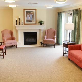 A cozy living room with armchairs, a sofa, and a fireplace.