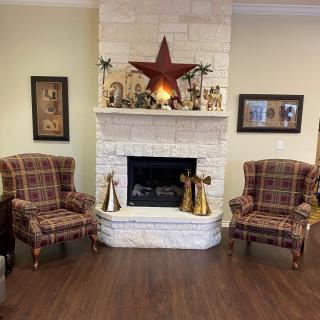 A cozy living room with a white stone fireplace, flanked by two plaid chairs and decorated with a large star on the mantel.