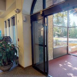 A building entrance with glass doors and an indoor plant.