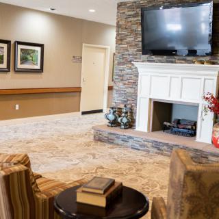 A cozy living room with a stone fireplace and mounted TV, featuring comfortable seating and tasteful decor.