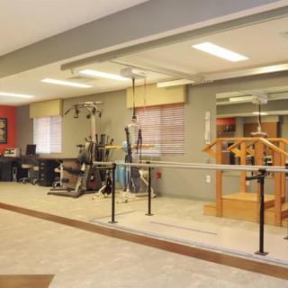 A well-equipped fitness and rehabilitation center with various exercise machines and mirrors reflecting the interior.