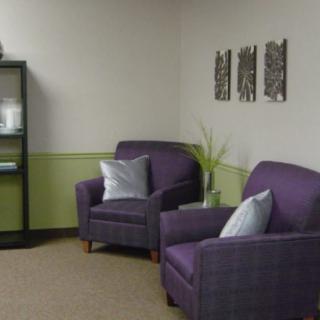 A cozy waiting room with purple chairs and decor.