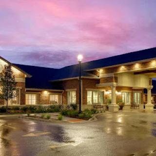 A modern hotel at dusk, reflecting vibrant colors in the sky after rain.