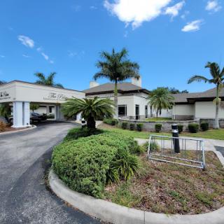 A modern building surrounded by palm trees and greenery under a clear blue sky.
