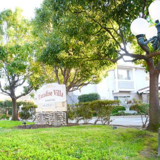 Entrance to the apartment complex surrounded by trees and greenery.