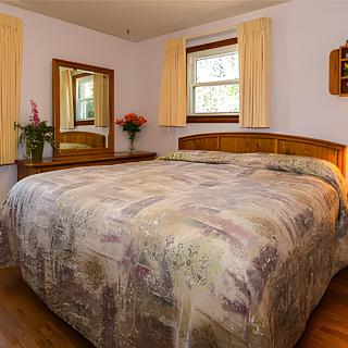 A cozy bedroom with a large bed, wooden furniture, and floral decorations.