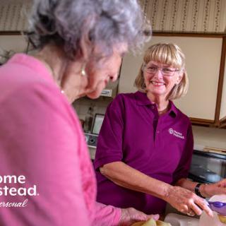 A caregiver assisting an elderly woman in the kitchen, showcasing warmth and companionship.