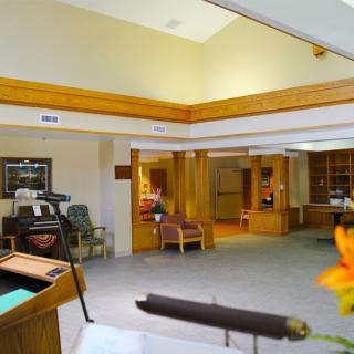 A brightly lit lobby with a reception desk and seating area, featuring wood accents and a carpeted floor.