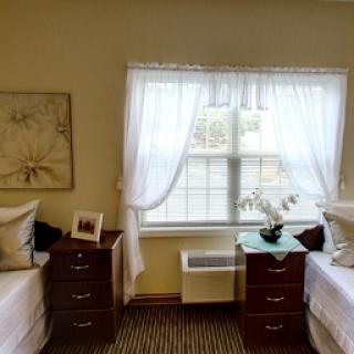 A cozy shared bedroom featuring two beds, warm lighting, and soft curtains.