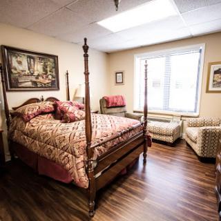 A cozy bedroom featuring a four-poster bed, warm lighting, and a comfortable seating area.